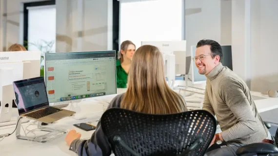 OrangeValleyer overlegt met een collega aan zijn bureau